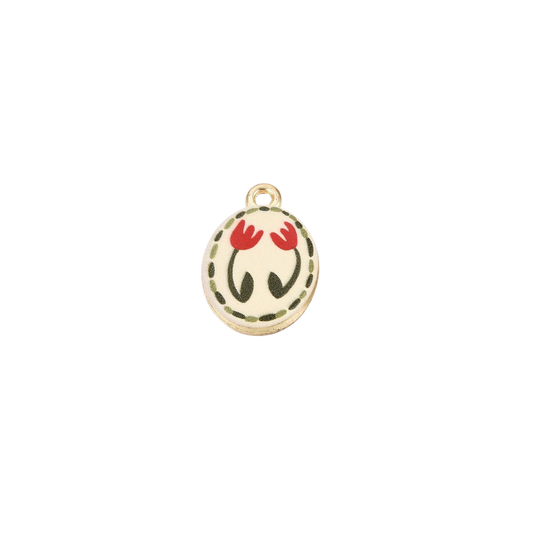 Gold oval charm featuring two red tulip illustrations with a dotted olive green border on a cream background