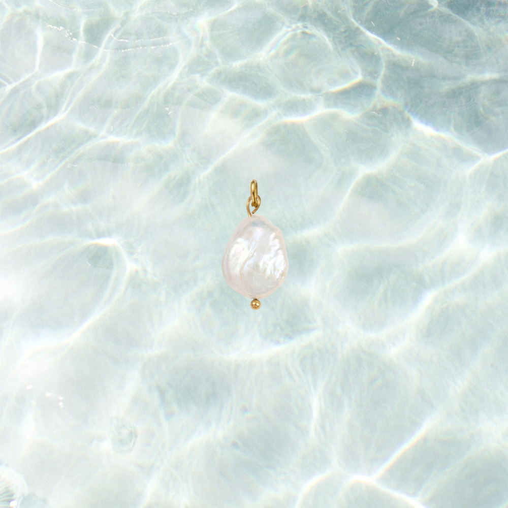Gold charm featuring a pearl drop on a shimmering water background.
