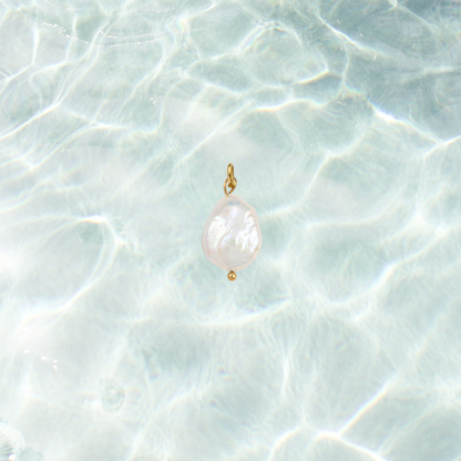 Gold charm featuring a pearl drop on a shimmering water background.