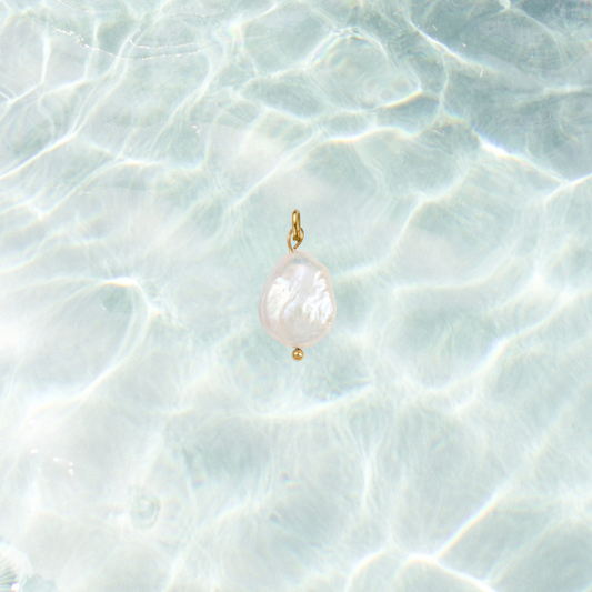 Gold charm featuring a pearl drop on a shimmering water background.