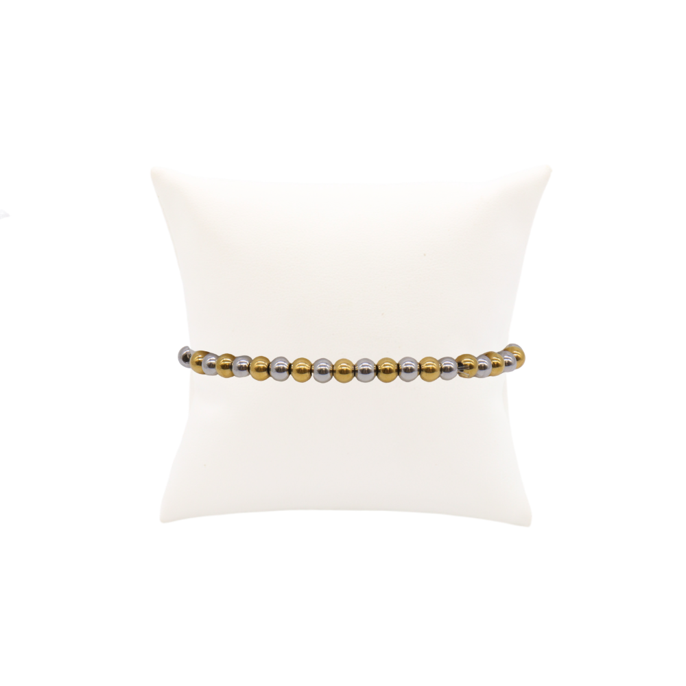 Mixed metal beaded stretch bracelet featuring alternating gold and silver stainless steel beads displayed on a white bracelet pillow against a white background
