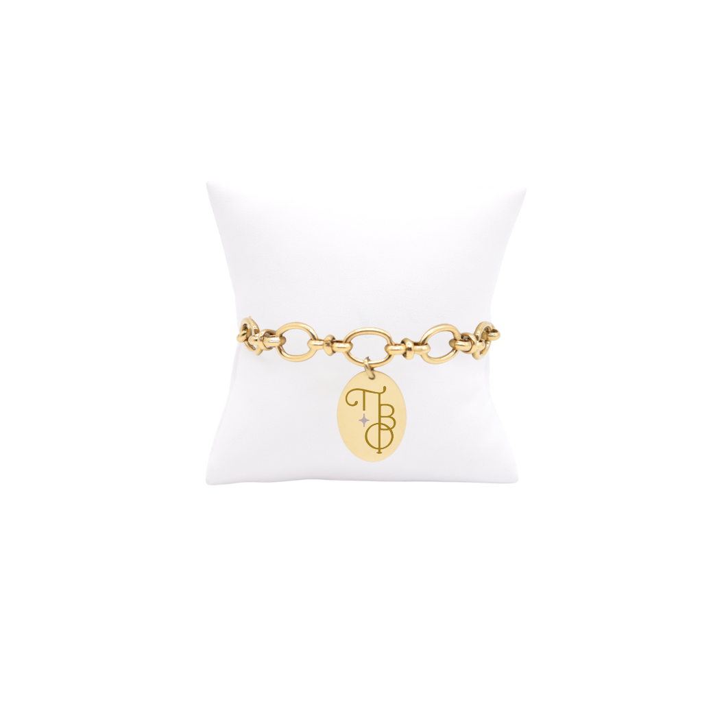 Pi Beta phi gold large link Evermore bracelet with large oval charm displayed on white pillow front view with new vertical/stacked greek letters