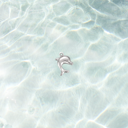 Silver dolphin charm on a shimmering water background, featuring a polished dolphin design with a pre-installed gold jump ring.