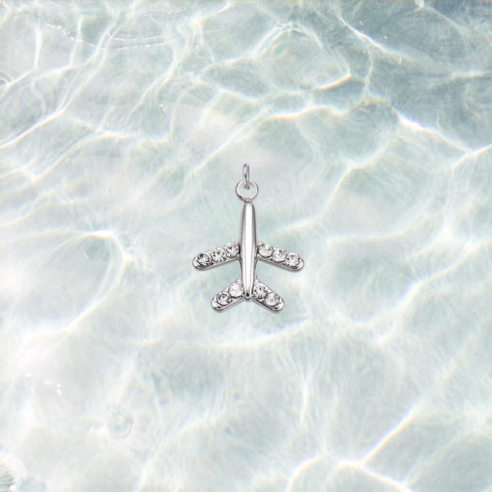 Silver waterproof airplane charm accented with rhinestones on the wings and tail, displayed on a shimmering light blue water background