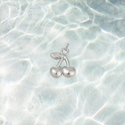 Silver waterproof cherry charm with a polished finish on a shimmering light blue water background.