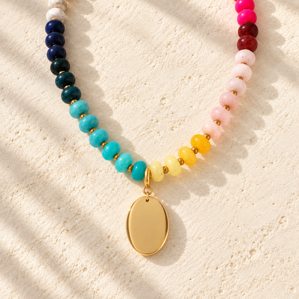 Desert Heirloom Beaded Necklace featuring turquoise, navy, pink, red, yellow, and cream beads with gold-tone accents and a smooth oval pendant.