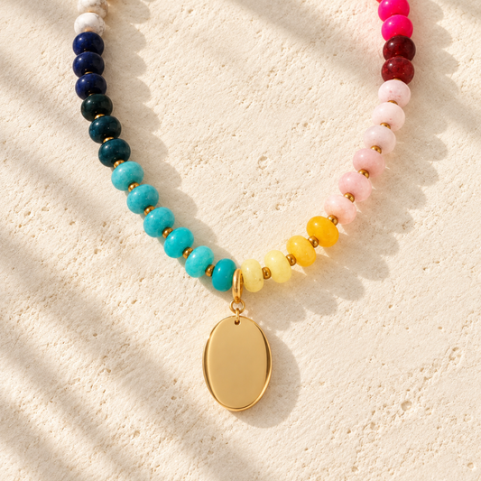 Desert Heirloom Beaded Necklace featuring turquoise, navy, pink, red, yellow, and cream beads with gold-tone accents and a smooth oval pendant.