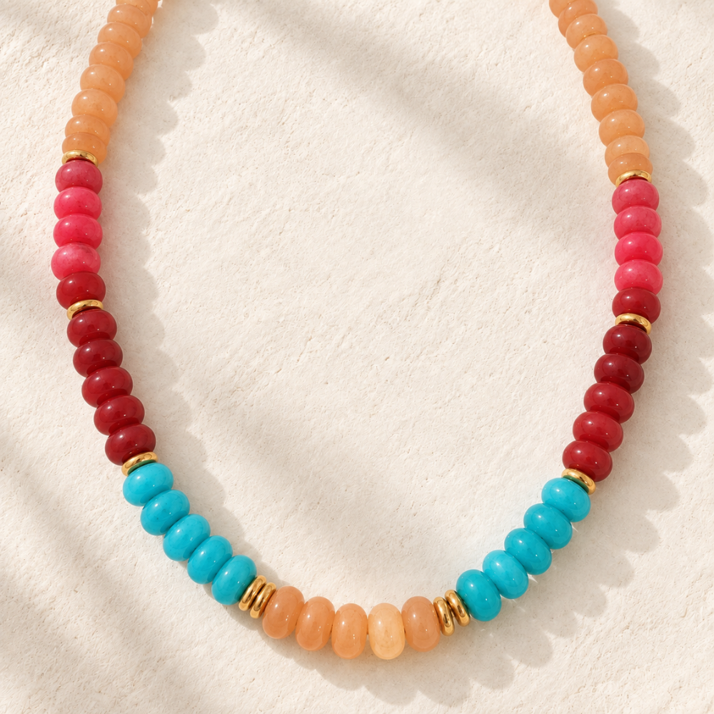 Desert Sky Beaded Necklace featuring peach, coral, deep red, and turquoise blue beads with polished gold-tone spacer accents.