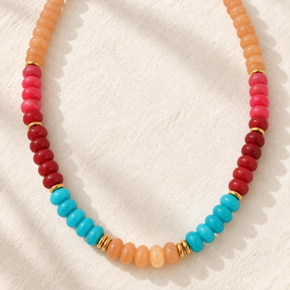 Desert Sky Beaded Necklace featuring peach, coral, deep red, and turquoise blue beads with polished gold-tone spacer accents.