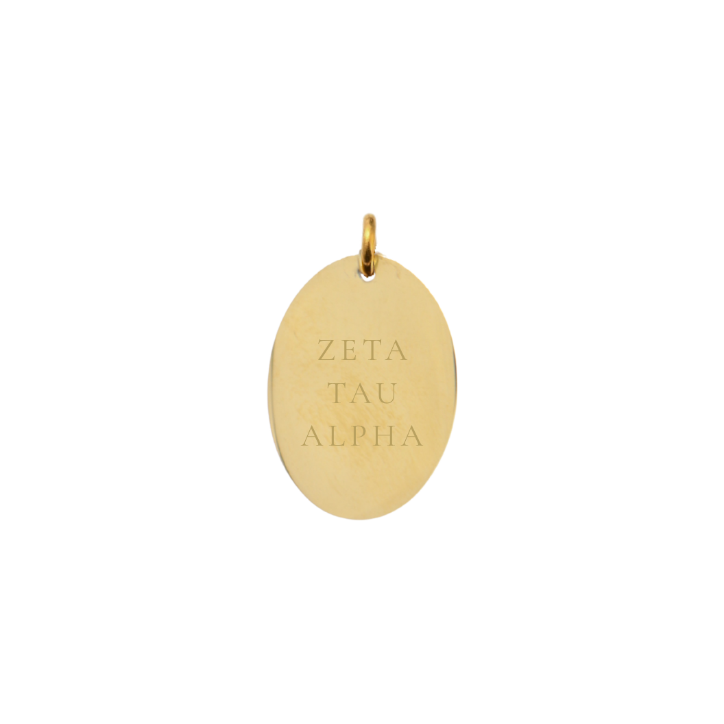 Gold pendant with 'ZETA TAU ALPHA' engraving on a white background